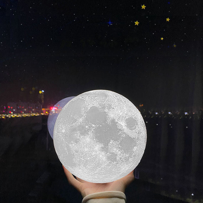 Hand holding the 3D moon lamp lit white against a night skyline