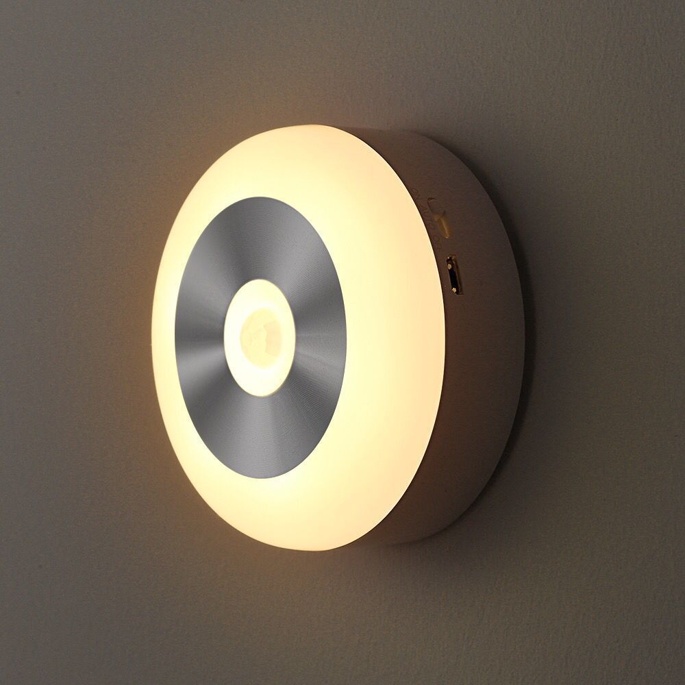 Round touch-control night light glowing warm, mounted on a wall