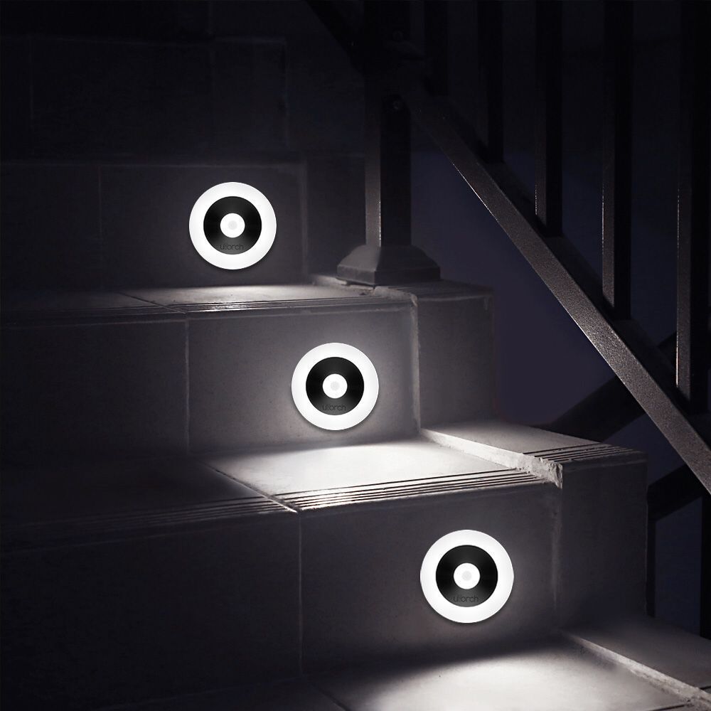 Three round night lights lit white along a dark staircase