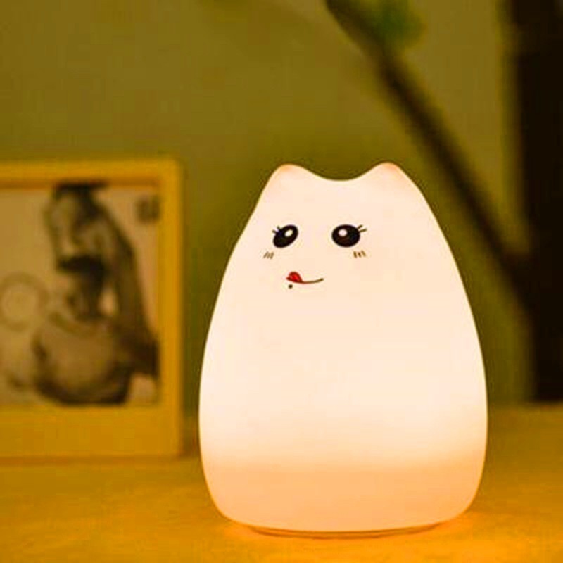 Silicone cat night light glowing warm beside a picture frame