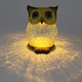 Owl solar garden light glowing warm, casting patterns on the surface below