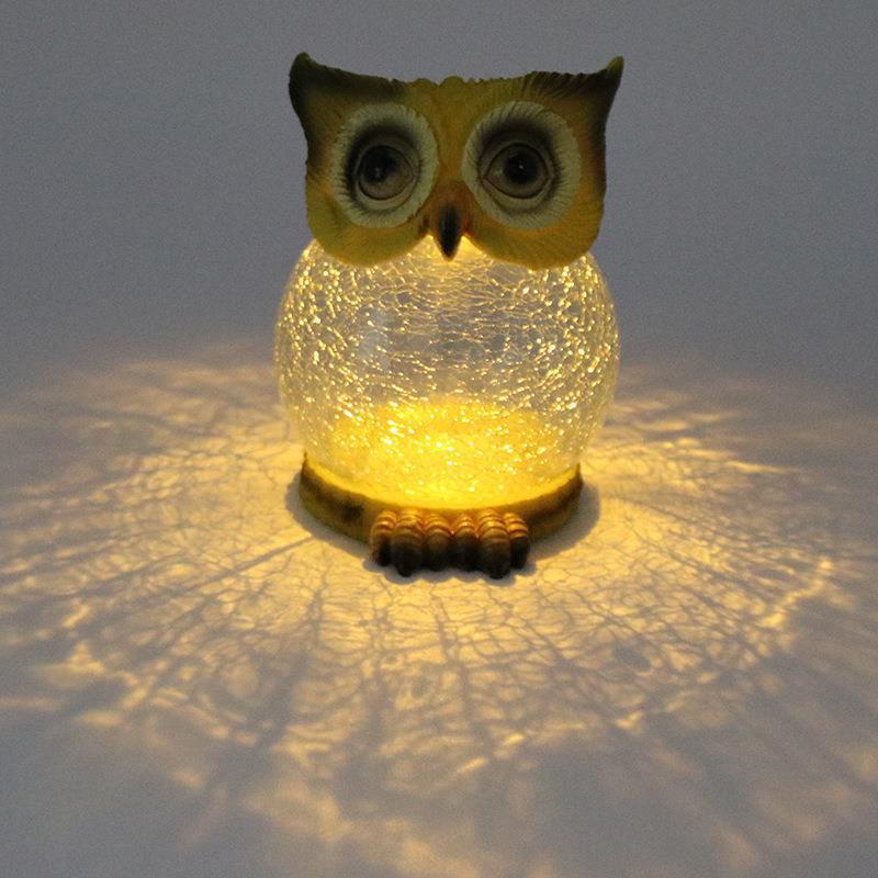 Owl solar garden light glowing warm, casting patterns on the surface below