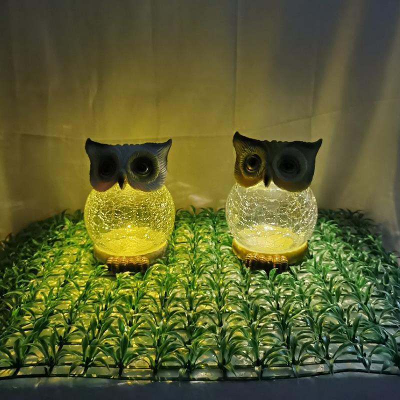 Two owl solar garden lights glowing warm on artificial grass