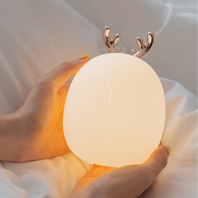 Hands cupping the deer night light as it glows warm