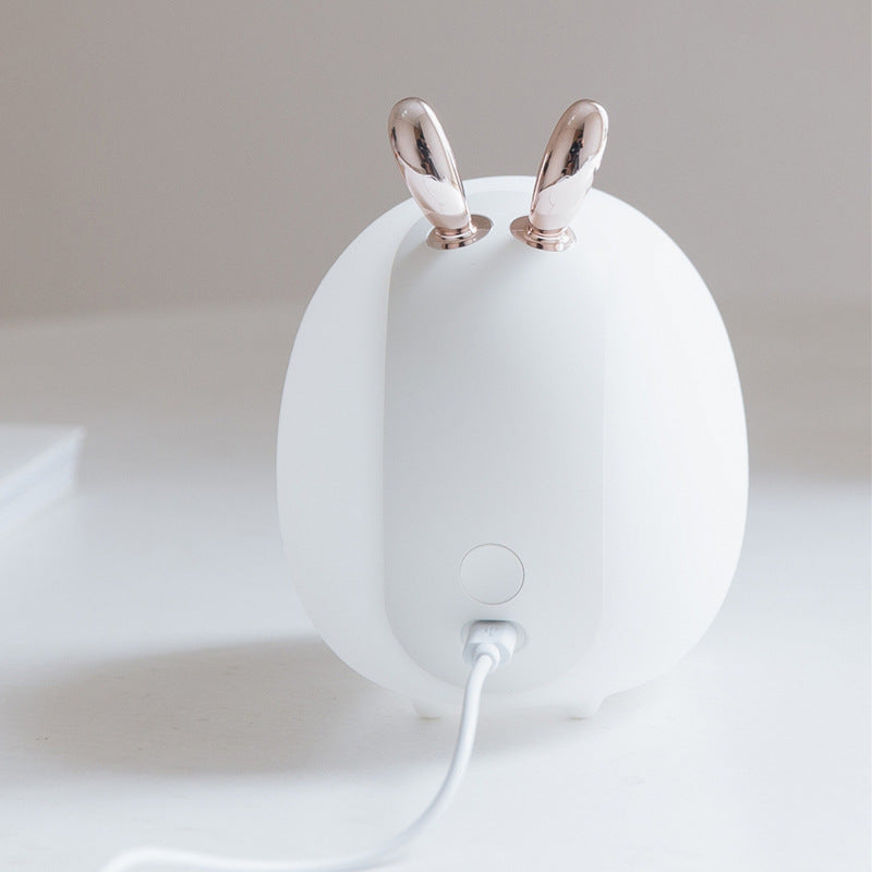 White silicone rabbit-ear night light with its USB charging cable