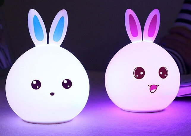 Two silicone rabbit night lights lit white and pink side by side
