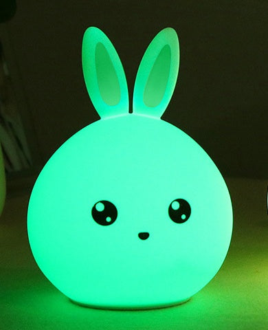 Silicone rabbit night light glowing green in a dark room