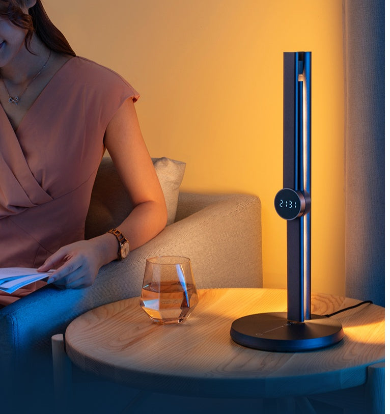 Person reading at a table with the dark blue reading lamp lit beside them