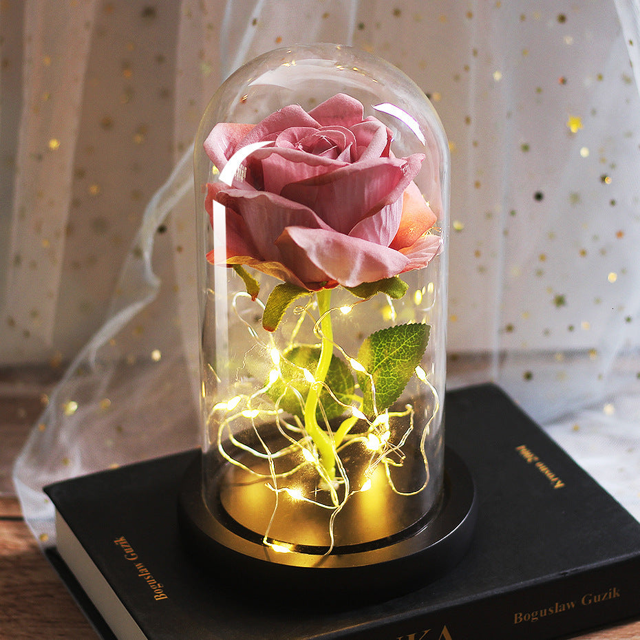 Pink and peach roses in a glass dome with fairy lights, gold base