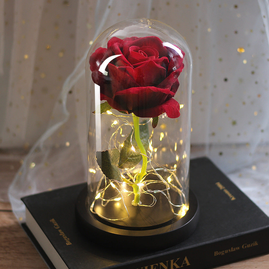 Two red roses in a glass dome with fairy lights on a black base
