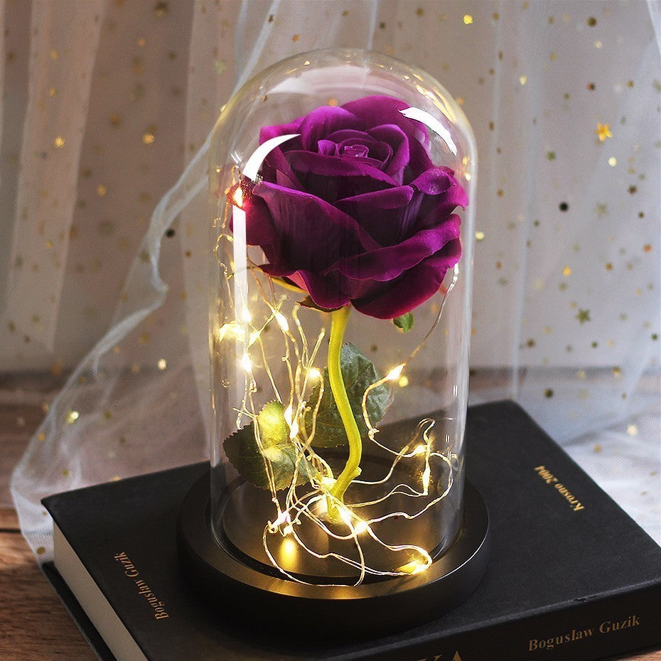 Purple rose in a glass dome with warm fairy lights, black base