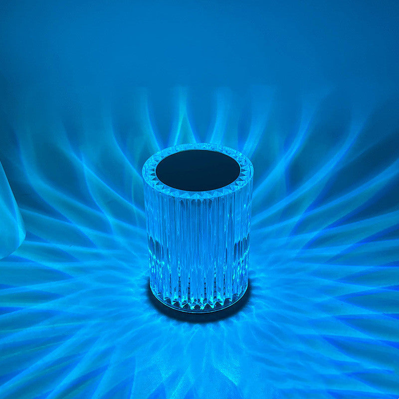 Ribbed crystal table lamp lit blue, casting fan patterns on the wall