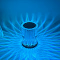 Ribbed crystal table lamp lit blue, casting fan patterns on the wall