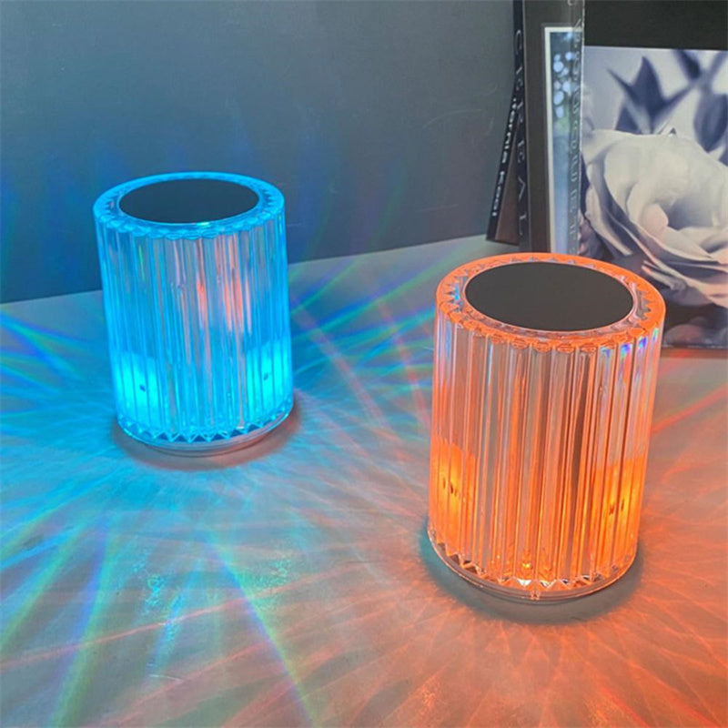 Two ribbed crystal lamps lit teal and orange on a desk