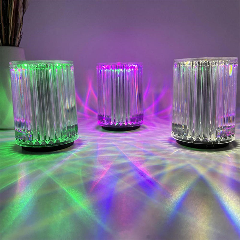 Three ribbed crystal lamps lit green, purple and clear against a green wall