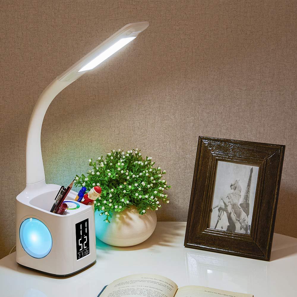 Desk lamp with a pen holder and LCD clock lit on a desk beside a plant and photo frame