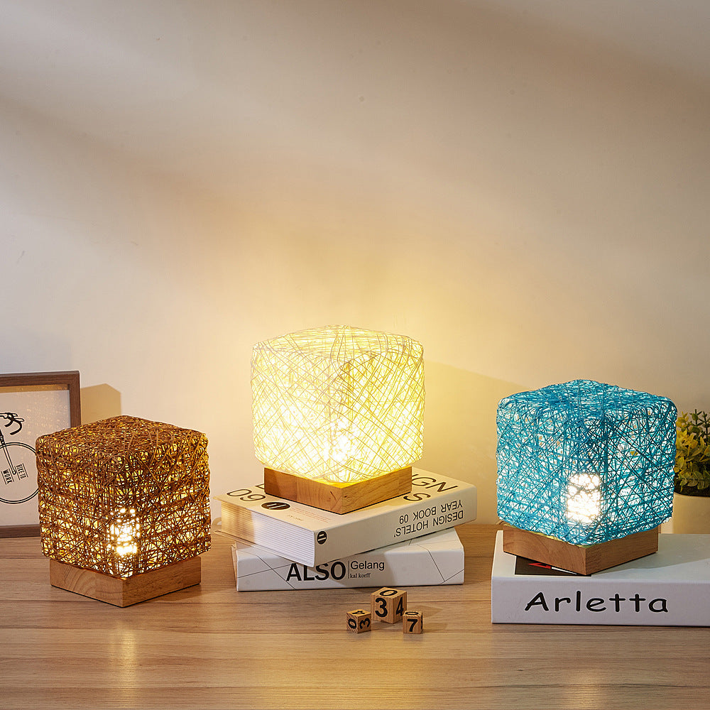 Three woven table lamps lit warm, gold and blue, standing on books