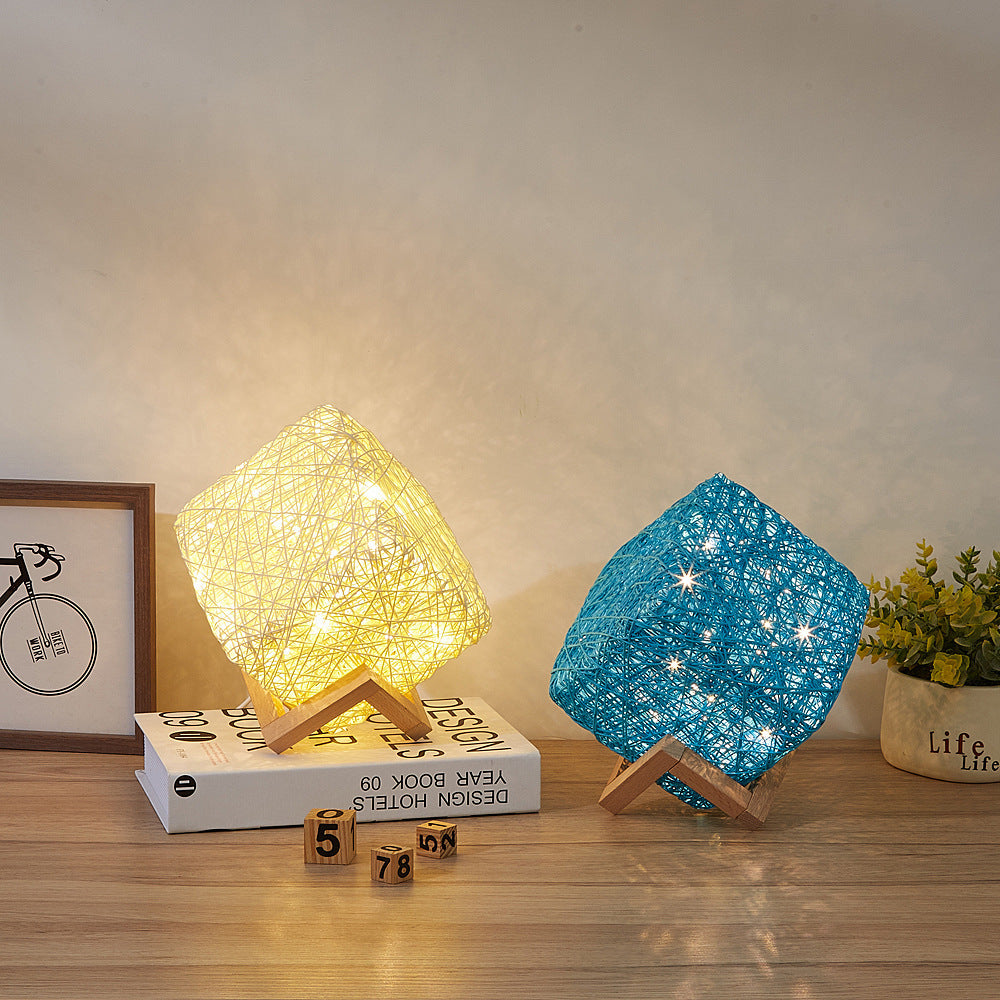 Gold cube and blue cube woven table lamps lit side by side