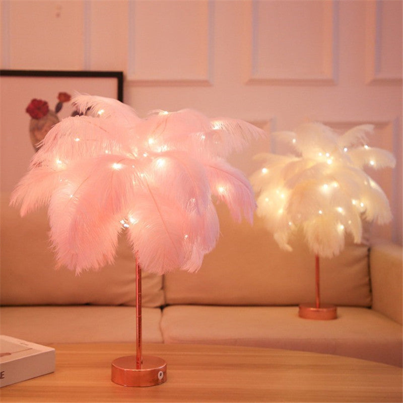Two pink feather table lamps lit on a sofa against a warm wall