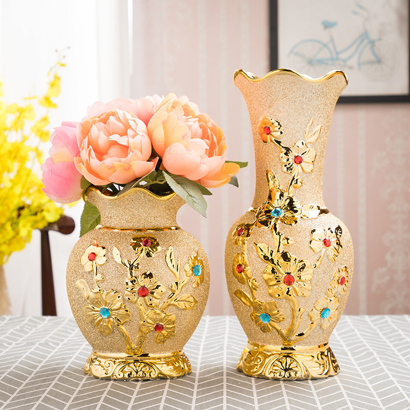 Two gold-patterned ceramic vases, one holding pink peonies