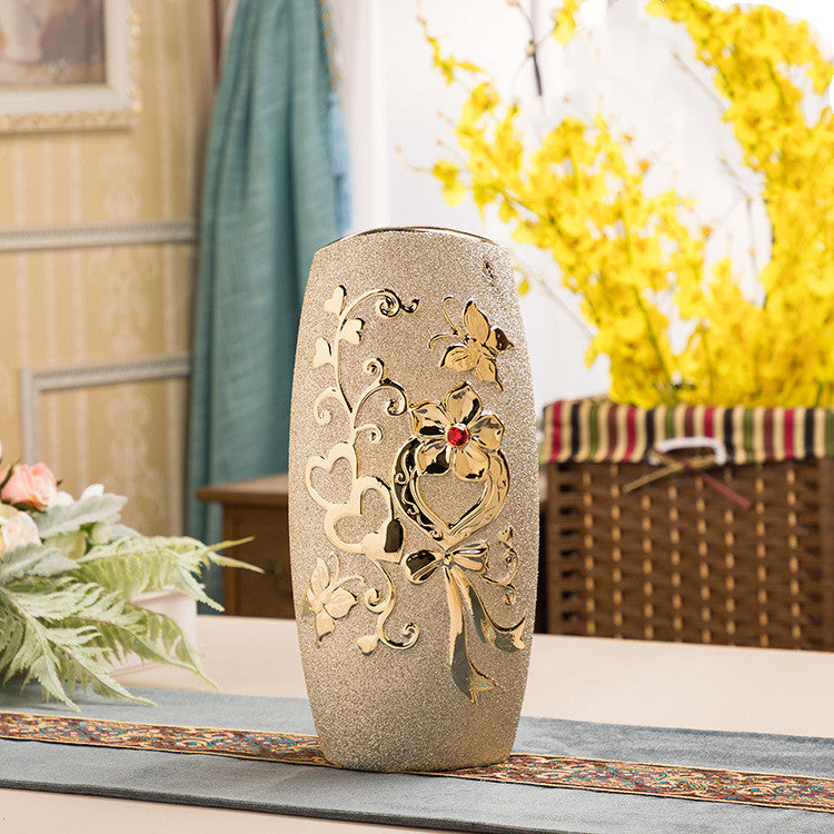 Cylinder ceramic vase with a gold scroll relief on a woven runner