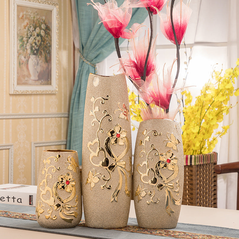 A group of gold-patterned ceramic vases holding pink magnolia stems
