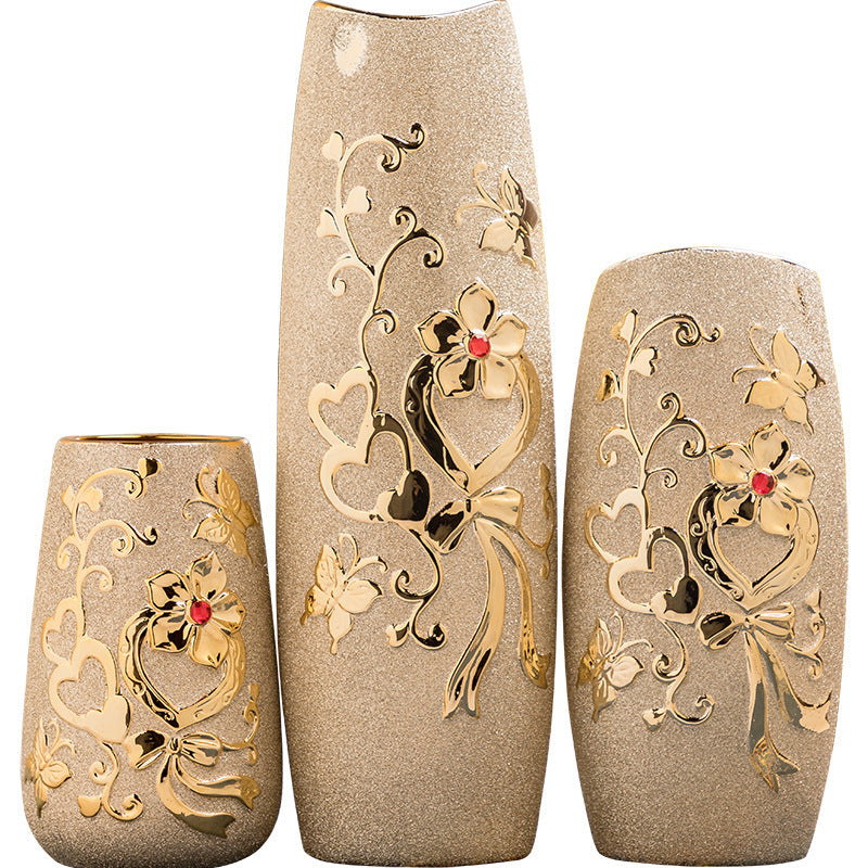 Three cylinder ceramic vases with gold relief patterns, plain background