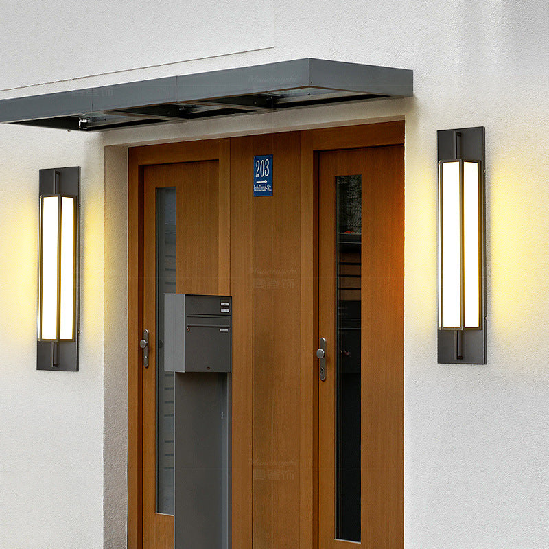 Two outdoor wall sconces lit either side of a wooden front door