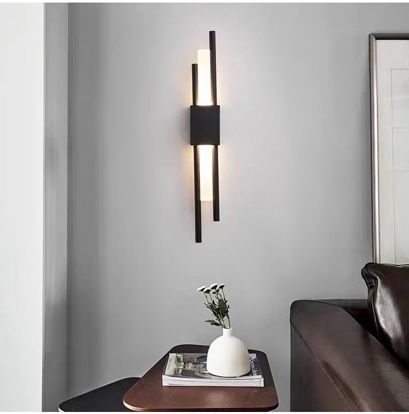 Black linear wall sconce lit above a side table beside a sofa