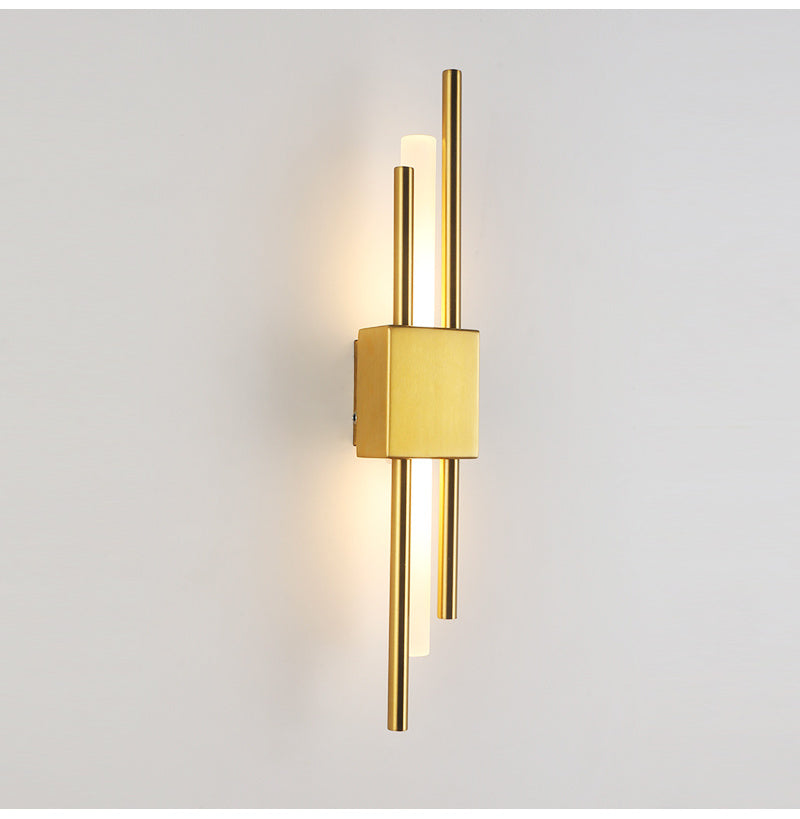 Gold linear wall sconce lit on a plain wall, front view