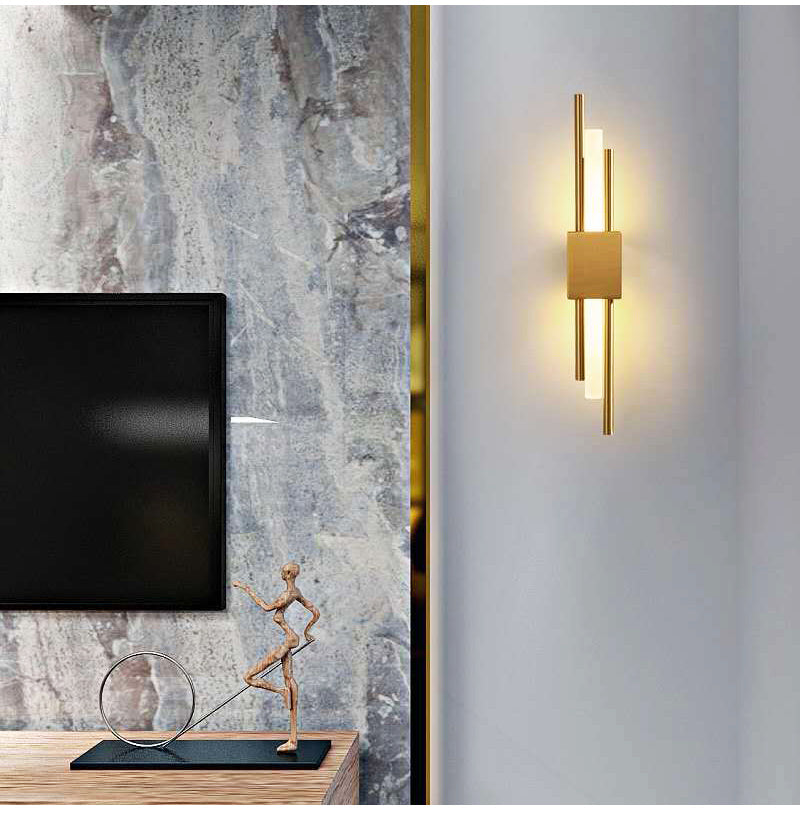 Gold linear wall sconce lit on a wall beside a television