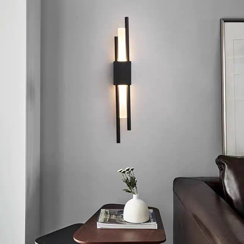 Black linear wall sconce lit above a side table with a vase