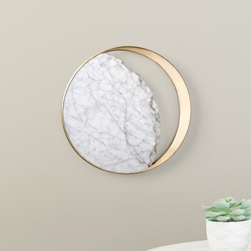 Round marble and gold wall sconce unlit on a plain wall